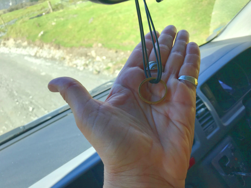 Mary's hand holding the ring in the van