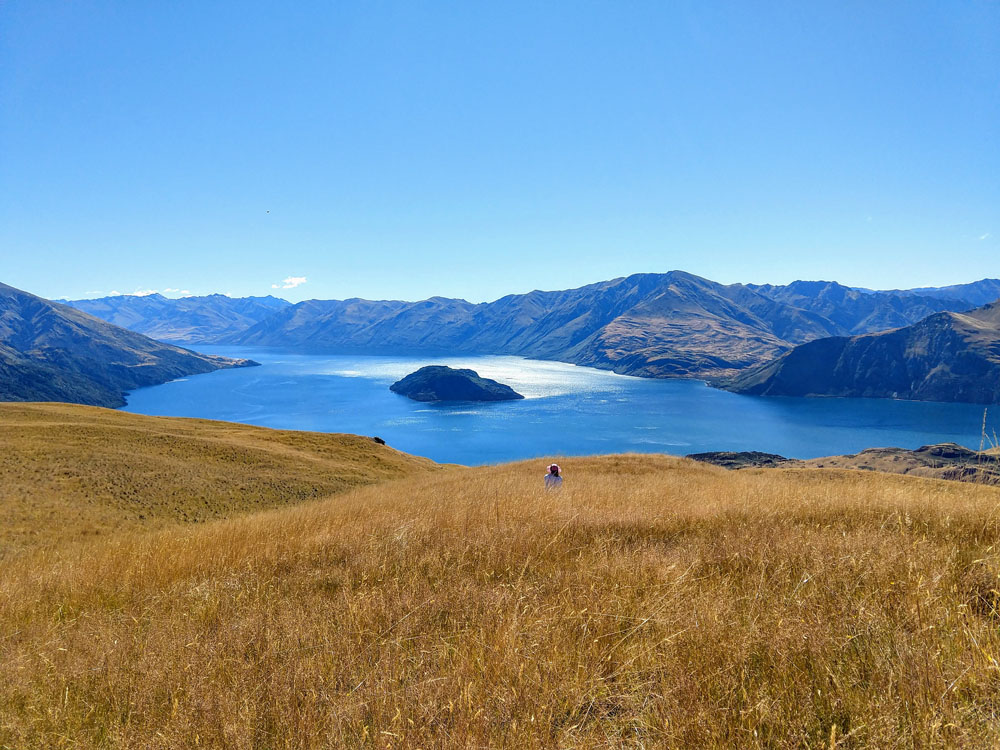 woman sitting alone in field with views of lake