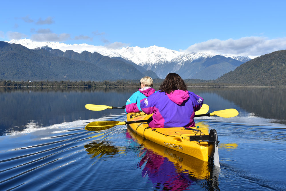 women in kayak with mountain views